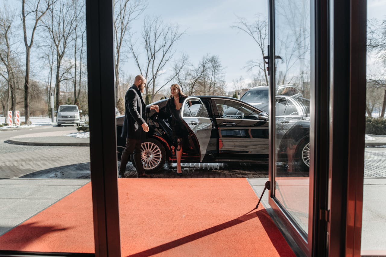 A woman getting out of a car and stepping on a red carpet at a public event